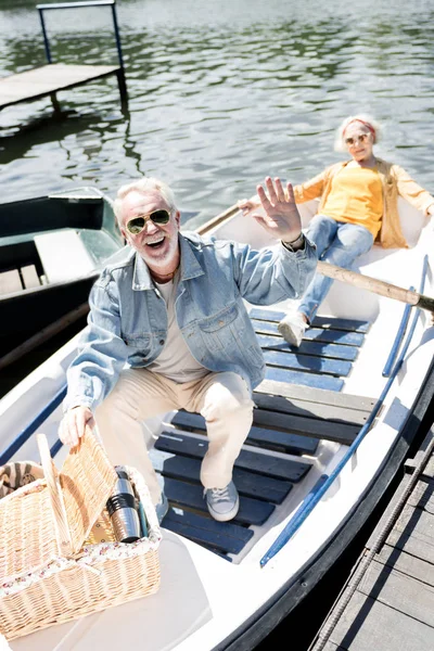 Pensionato emotivo sorridente e agitando la mano mentre seduto sulla barca — Foto Stock