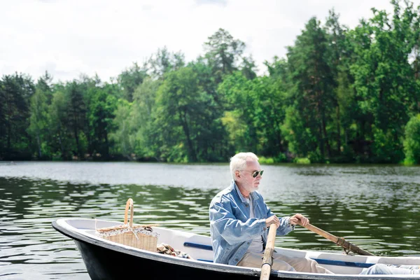 Pensionista sério olhando pensativo enquanto remo seu barco — Fotografia de Stock