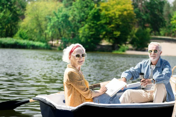 Fröhliche Rentner lächeln und genießen das gemeinsame Bootfahren — Stockfoto