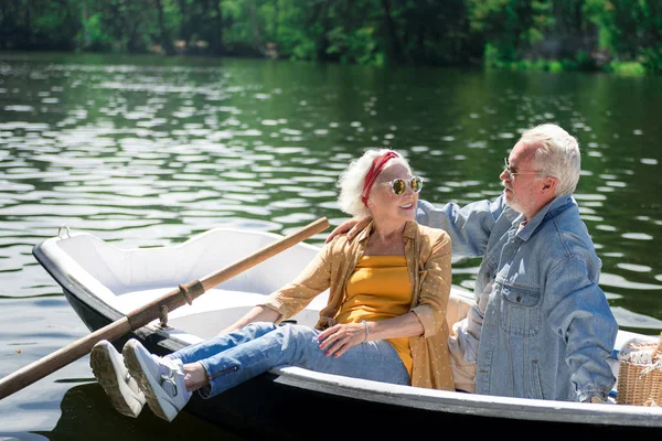 Bela aposentada olhando para o marido enquanto estava sentada no barco com ele — Fotografia de Stock
