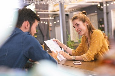 Ziyaretçiye yaslanmış ve belgeleri arayan genç barmen