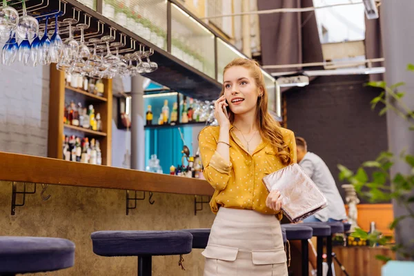 Calma jovencita de pie en el mostrador del bar y hablando por teléfono — Foto de Stock