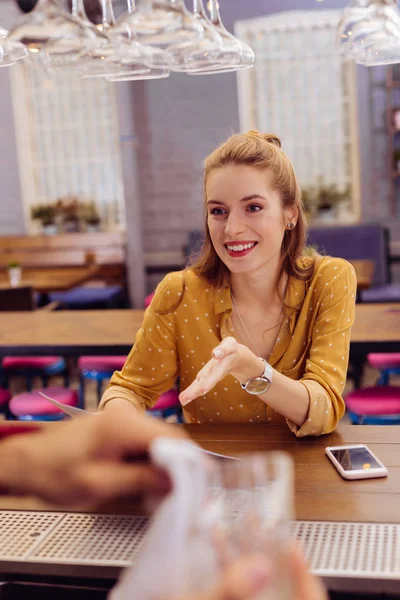 Cute young girl smiling to the barman while visiting the bar