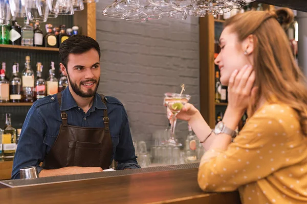 Příjemný barman při pohledu na pití návštěvníka a usmívá se — Stock fotografie