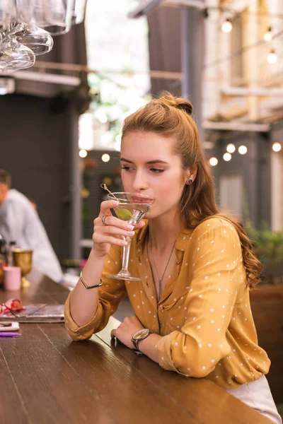 Красивая молодая девушка пьет алкоголь, находясь в баре — стоковое фото