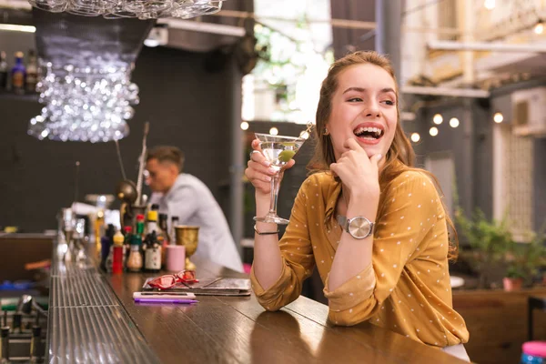 Jovencita positiva riendo mientras está sentada en el bar — Foto de Stock