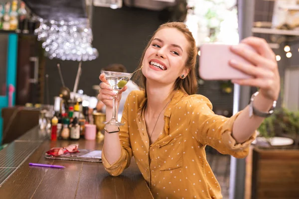 Όμορφη νεαρή κοπέλα που κρατά ποτήρι αλκοόλ και λήψη selfie — Φωτογραφία Αρχείου