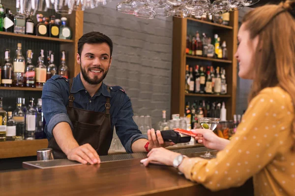 Neşeli barmen müvekkilinin fatura ödeme sırasında gülümseyen