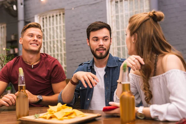 Three young people talking and eating in the bar