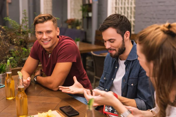 Homem emocional usando gestos enquanto conversa com amigos no bar — Fotografia de Stock