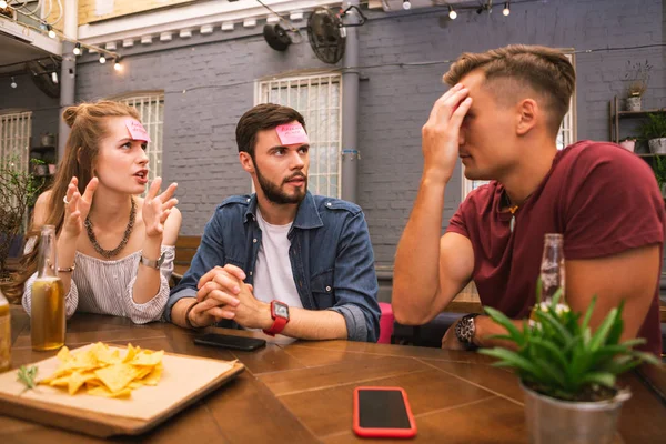 Amigos curiosos usando gestos ao explicar palavras no jogo — Fotografia de Stock