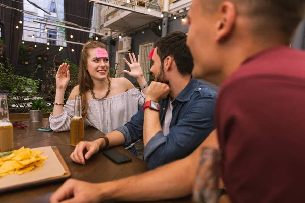 Expressive jeune femme souriant et jouer à des jeux avec des amis — Photo