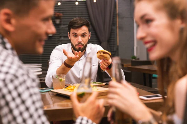 Молодой человек выглядит удивленным, когда его друзья пьют без него — стоковое фото