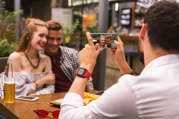 Romantyczna para uśmiechnięty fotografowane przez ich przyjaciel — Zdjęcie stockowe