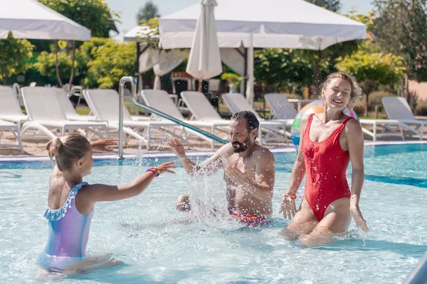 Encantada familia agradable jugando juntos en la piscina — Foto de Stock