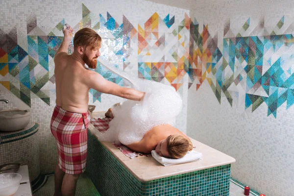 Bom homem qualificado fazendo uma massagem de espuma — Fotografia de Stock