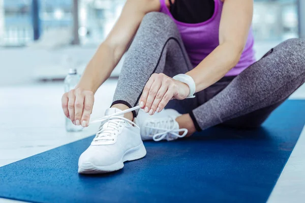 Vigorous mature woman putting on sneakers before workout — Stock Photo, Image