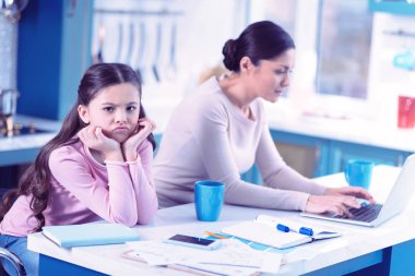 Little girl feeling angry while her busy mother paying no attention to her clipart