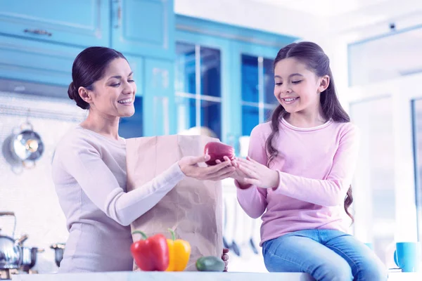 Красивая молодая женщина дарит свежее яблоко своей дочери и улыбается — стоковое фото
