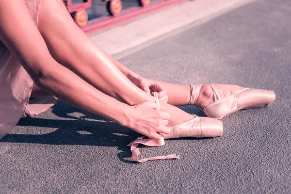 Приятная молодая балерина застегивает туфли. — стоковое фото