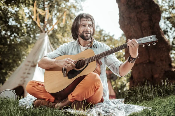 Piacevole uomo con chitarra seduta sull'erba — Foto Stock