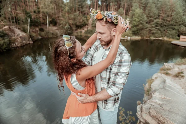 Engraçado encaracolado namorada colocando seu lindo capacete floral em seu homem bonito — Fotografia de Stock
