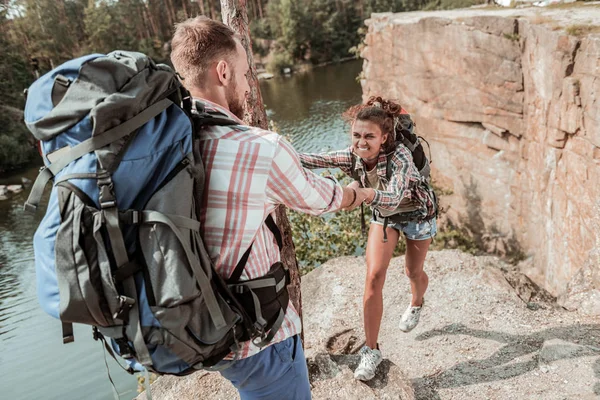 Curly dark-haired woman with heavy backpack feeling tired hiking with her man — Stock Photo, Image