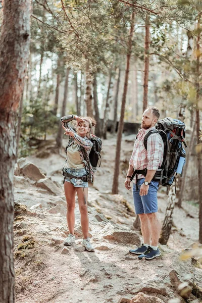 Femme aux cheveux bruns avec sac à dos montrant petit écureuil dans la forêt son homme — Photo
