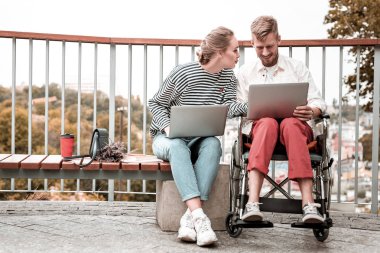 Devre dışı meslektaşı ile oturma ve dizüstü bilgisayarda çalışan adam