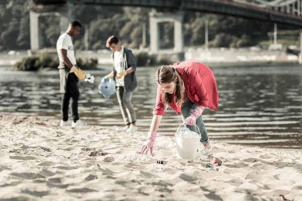 Chica de cabello oscuro con guantes rosados que participan en el trabajo voluntario en la playa — Foto de Stock