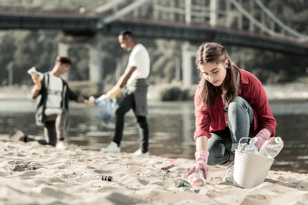 Güzel ilk sınıf öğrencisi gönüllü süre sahilde boş şişeleri toplama — Stok fotoğraf