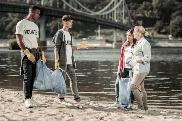 Tres voluntarios activos hablando con su jefe de equipo después de limpiar la playa — Foto de Stock