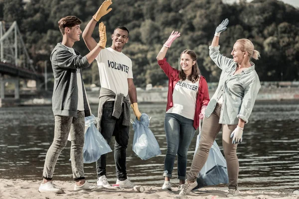 Felices voluntarios radiantes que se dan choco entre sí después de completar las tareas — Foto de Stock