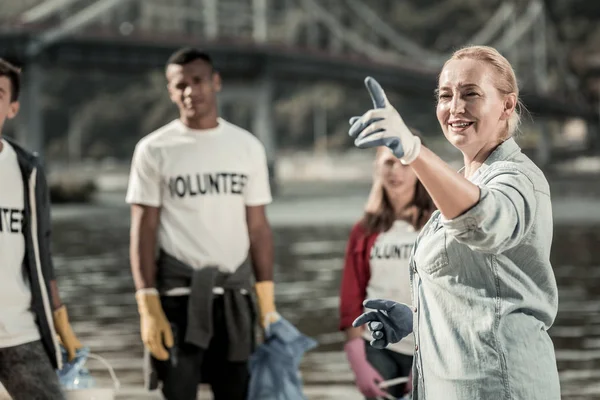 Volwassen blonde-haired vrouw blauw handschoenen in gesprek met jonge vrijwilligers — Stockfoto