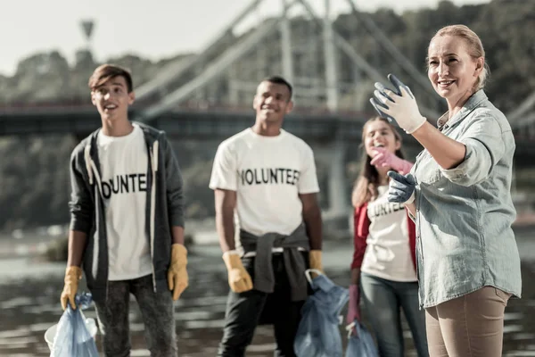 Compañía de jefe de equipo y tres jóvenes voluntarios limpiando la playa — Foto de Stock