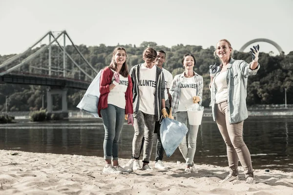 Verantwoordelijke leerkracht en vier actieve studenten vrijwilligerswerk in de buurt van de rivier samen — Stockfoto