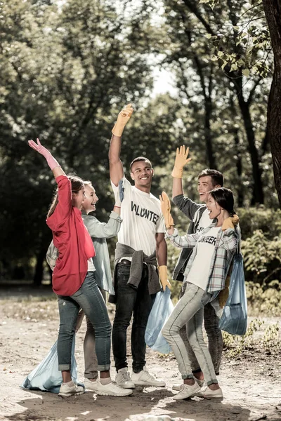 Actieve stralend vrijwilligers geven hoge vijf aan elkaar na het schoonmaken van het bos — Stockfoto