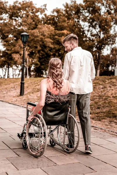 Gelukkig man zijn handicap vriendin kijken tijdens het wandelen met haar — Stockfoto