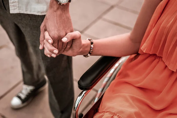 Jolie fille handicapée assise en fauteuil roulant et tenant la main du petit ami — Photo