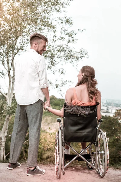 Behindertes Mädchen sitzt im Rollstuhl und hält Händchen mit Freund — Stockfoto