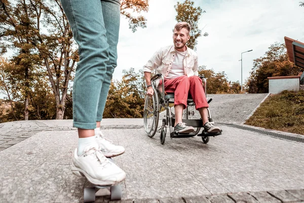 Handikappade mannen sitter i rullstol och tittar på penny styrelsen — Stockfoto