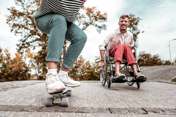 Uomo disabile attivo in competizione con il suo amico e cavalcando la sua sedia a rotelle — Foto Stock