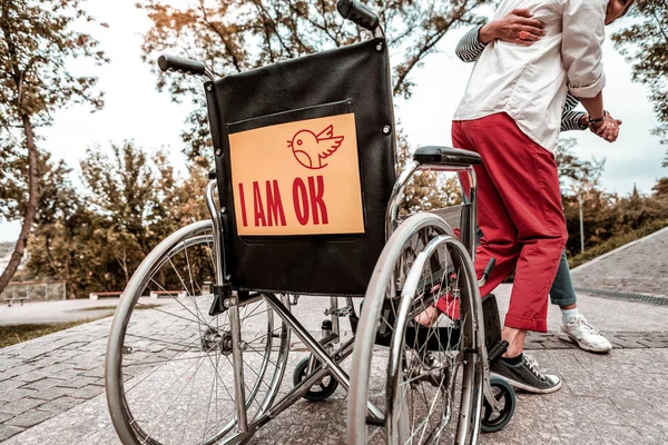 Gros plan du fauteuil roulant avec deux personnes debout près — Photo