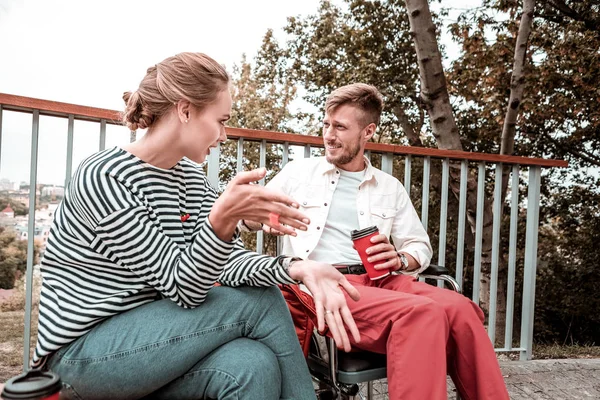 Femme émotionnelle assise à côté d'un homme handicapé et lui parlant — Photo