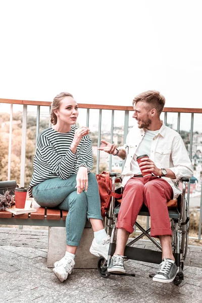 Man in rolstoel zitten en kijken naar zijn nieuwsgierig vriend tijdens een gesprek — Stockfoto
