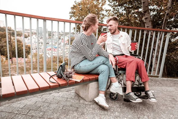 Vrolijke man in de rolstoel zitten en praten met zijn vriend in park — Stockfoto