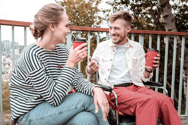 Man in wheelchair laughing while talking to the young woman