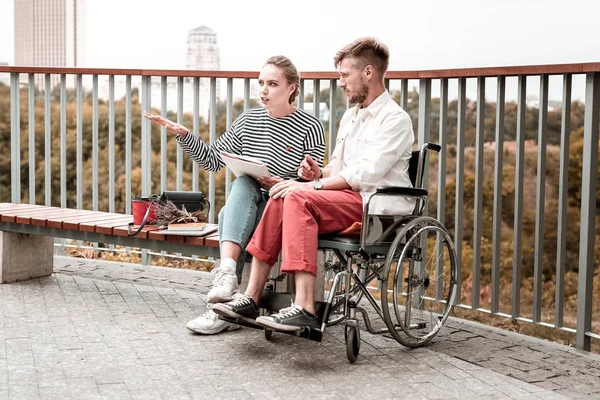 Serious hombre discapacitado mirando a su amigo mientras está sentado en el parque con ella — Foto de Stock