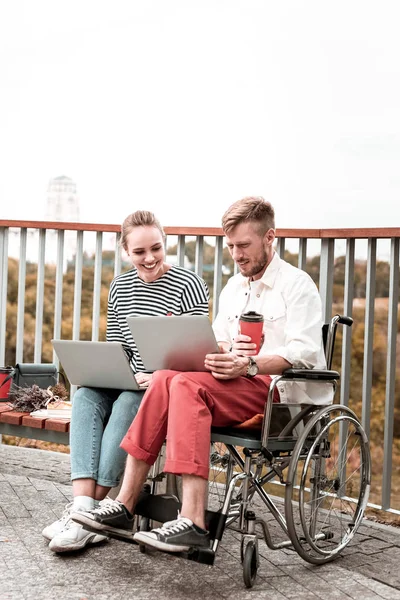 Młody mężczyzna siedzi na wózku i patrząc na laptopa — Zdjęcie stockowe