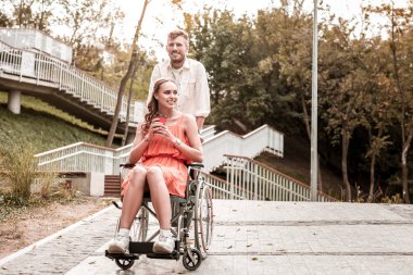 Mutlu kız sıcak kahve ve sakin adam tekerlekli iterek zevk